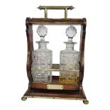 AN EDWARDIAN OAK AND BRASS TANTALUS Having a single carry handle and scrolled oak frame,