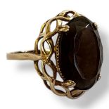 A VINTAGE 9CT GOLD AND SMOKY QUARTZ RING The oval faceted cut stone in a pierced design. (size P)