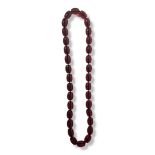 A STRING NECKLACE OF THIRTY-TWO LARGE OVAL AMBER BEADS. (length 41cm) Condition good