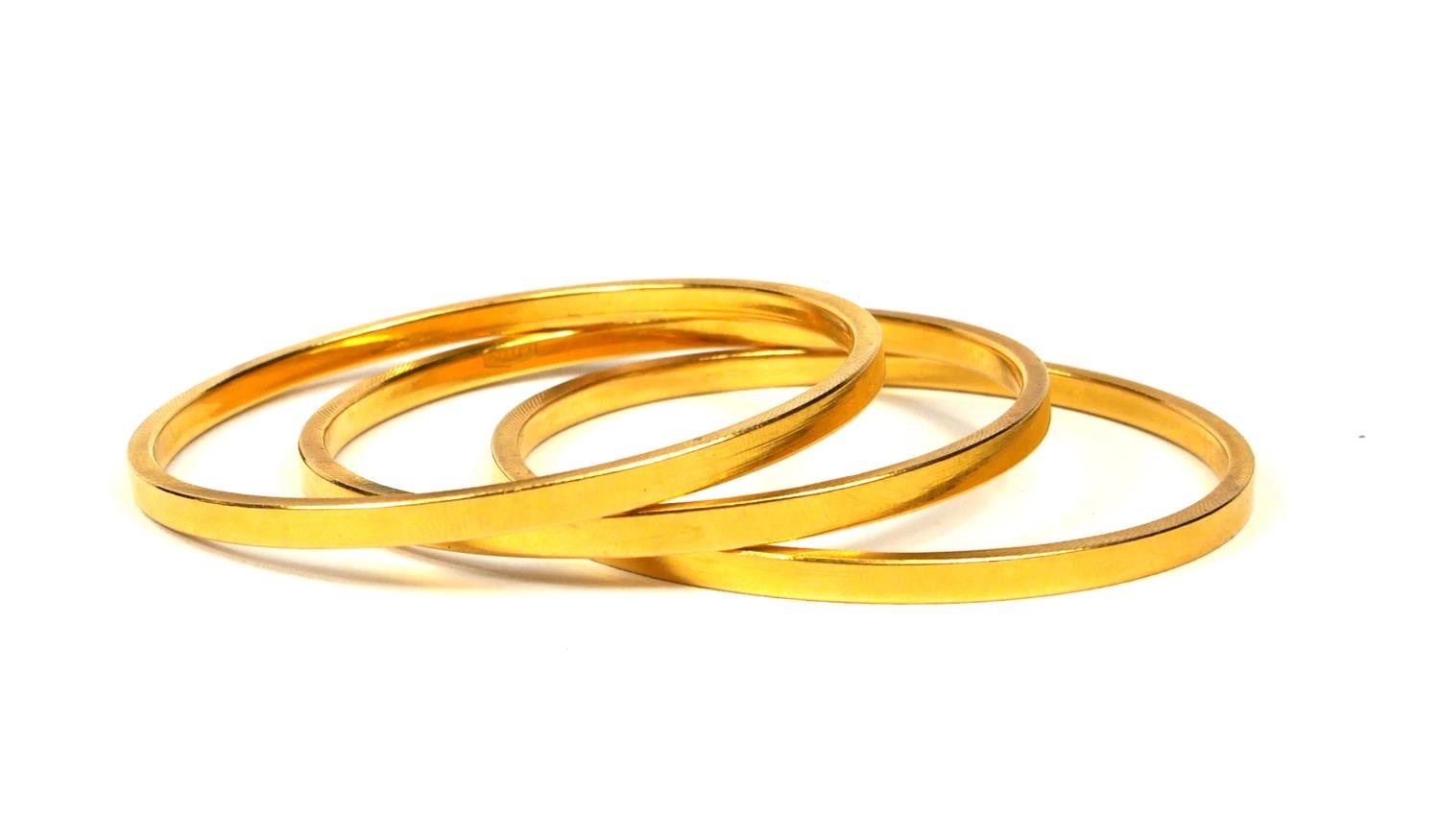 THREE 21CT GOLD BANGLES Having textured sides and polished interior and exterior finish. (diameter