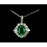 AN 18CT WHITE GOLD OVAL EMERALD AND DIAMOND CLUSTER PENDANT on an 18ct white gold chain. (Approx