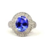 AN 18CT WHITE GOLD LARGE OVAL TANZANITE & DIAMOND RING, The tanzanite surrounded by a double halo of