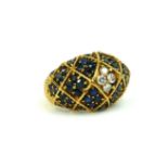 A VINTAGE YELLOW METAL, DIAMOND AND SAPPHIRE BOMBE RING Having an arrangement of round cut