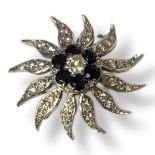 AN 18CT WHITE GOLD, DIAMOND AND SAPPHIRE STAR BROOCH The central round cut diamond edged with