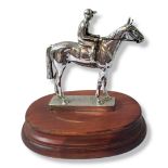 AN ART DECO CHROME RACEHORSE AND JOCKEY Standing pose on a carved wooden base. (approx 12cm)