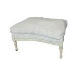 A FRENCH INVERTED BOW FRONTED HEARTH STOOL In a cream fabric upholstery with loose cushion on a