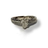 AN 18CT WHITE GOLD AND DIAMOND RING Having a pear cut diamond to centre flanked by diamond set