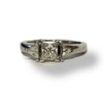 A PLATINUM AND DIAMOND RING Having a central Princess cut diamond edged with a trillion cut diamond.