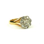 A VINTAGE YELLOW METAL AND DIAMOND CLUSTER RING Having an arrangement of round cut diamonds in a