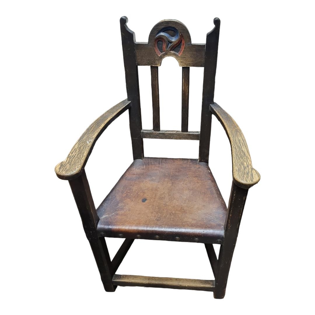 IN THE MANNER VOYSEY AN ARTS AND CRAFTS PERIOD OAK OPEN ARMCHAIR Tan leather seat. (58cm x 52cm x