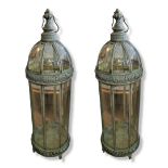 A LARGE PAIR OF VERDIGRIS BRASS AND EIGHT GLASS FLOOR STANDING STORM LANTERNS With domed top and