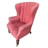 A 19TH CENTURY MAHOGANY UPHOLSTERED WINGBACK ARMCHAIR Raised on turned legs terminating on brass