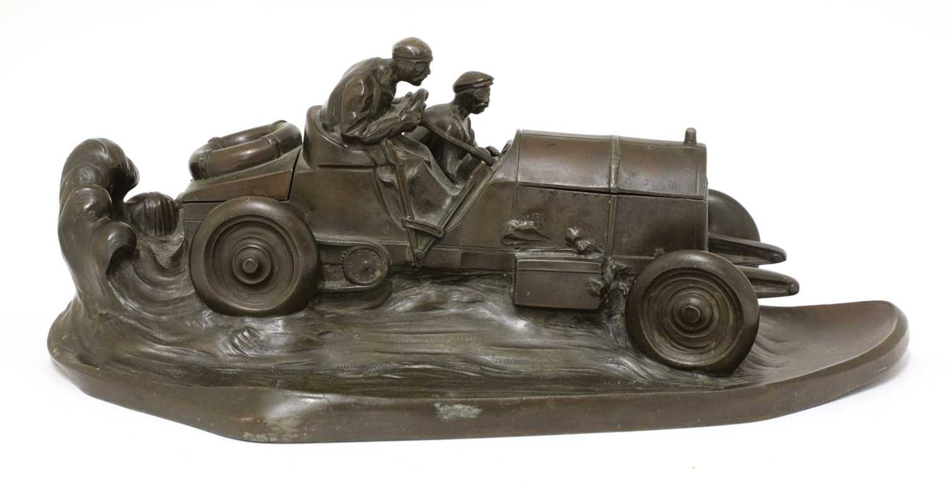 A Kayser patinated spelter desk stand in the form of a racing car,