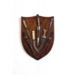 A wooden shield with seven Middle Eastern daggers,