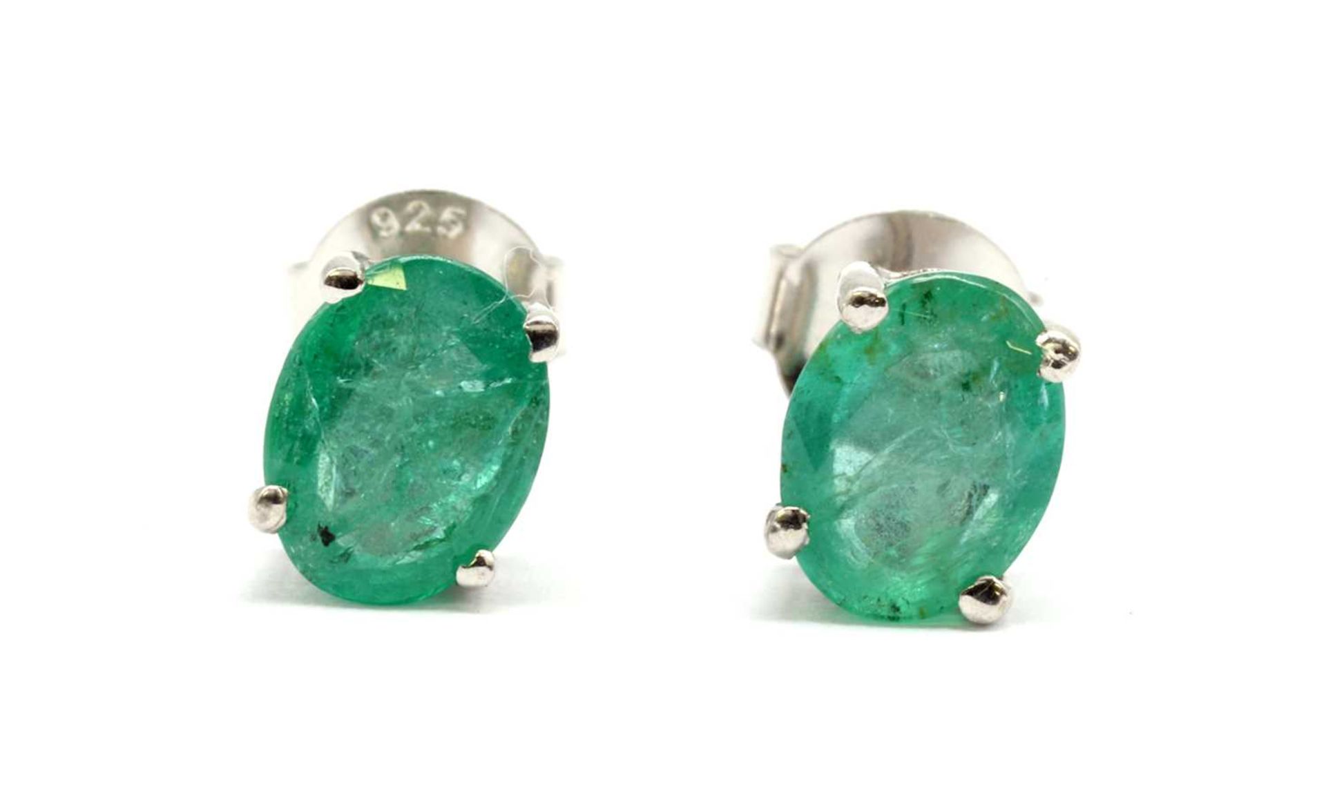 A pair of silver single stone emerald stud earrings,