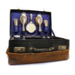 An Edwardian crocodile skin suitcase with a silver vanity set,