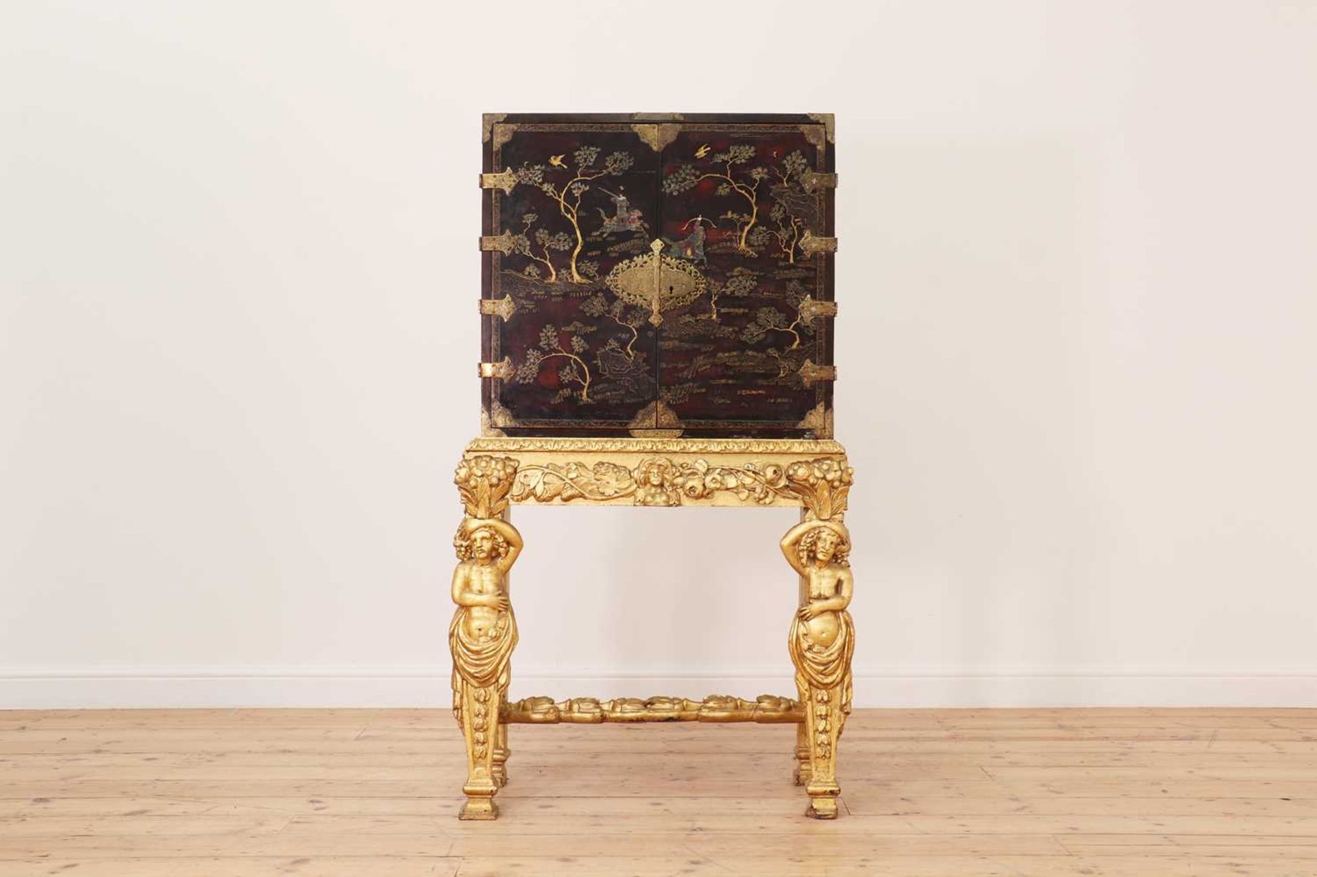 A lacquered, inlaid and gilt-heightened cabinet on stand,