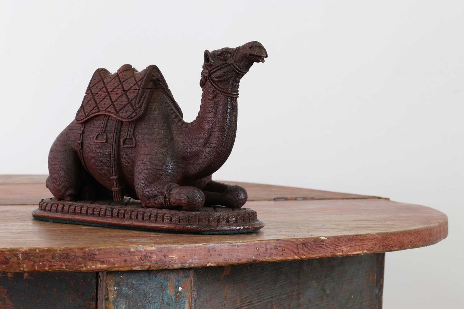A carved hardwood inkwell in the form of a seated camel,