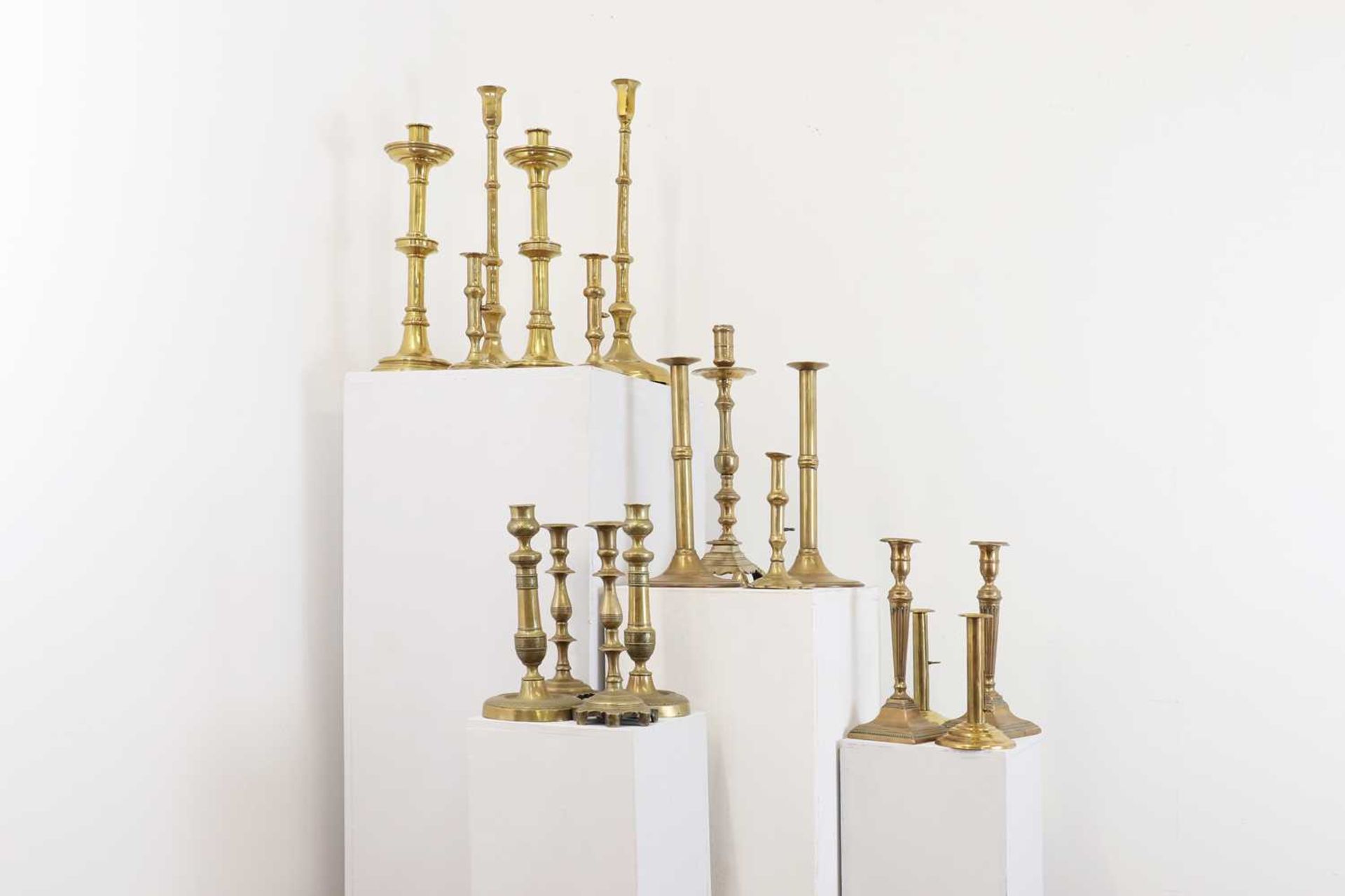 A large collection of brass candlesticks,