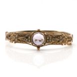 An Edwardian gold amethyst and split pearl oval hinged bangle,