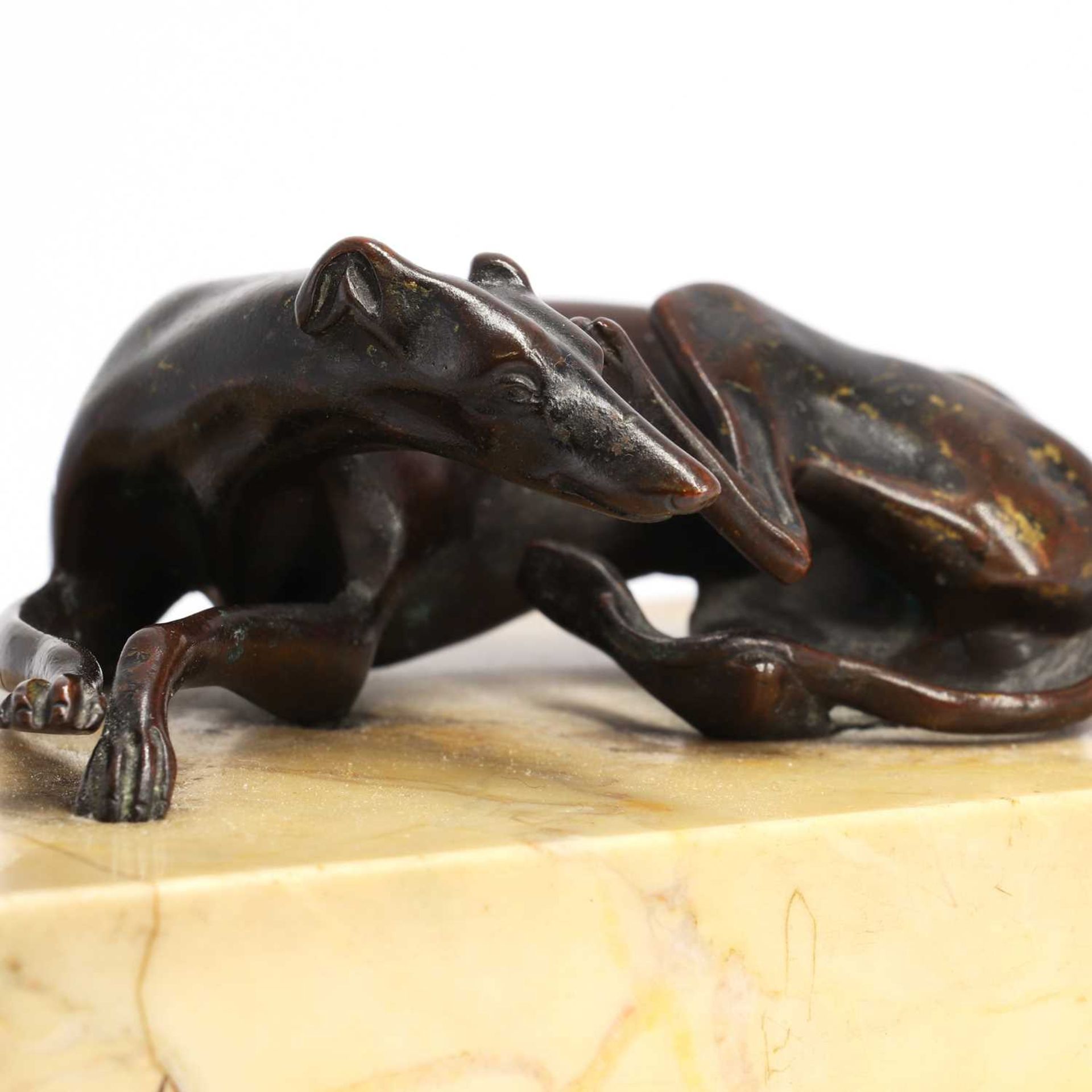A Regency bronze figure of a resting greyhound,