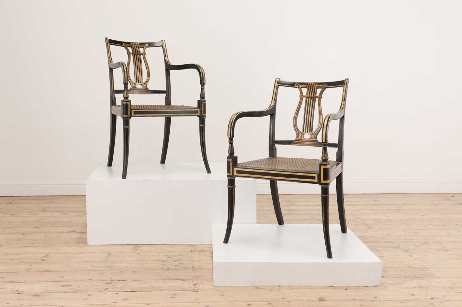 A pair of Regency ebonised and parcel-gilt armchairs,