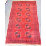 A large red ground Belouch-style carpet having twelve guls (some wear) (approx. 305cm x 185cm)