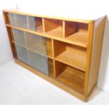 A mid-20th century bleached-oak side cabinet, sliding glass doors enclosing shelves, raised on