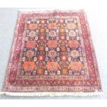 A thick pile hand-knotted Eastern rug – stylised gul pattern against a dark ground and within