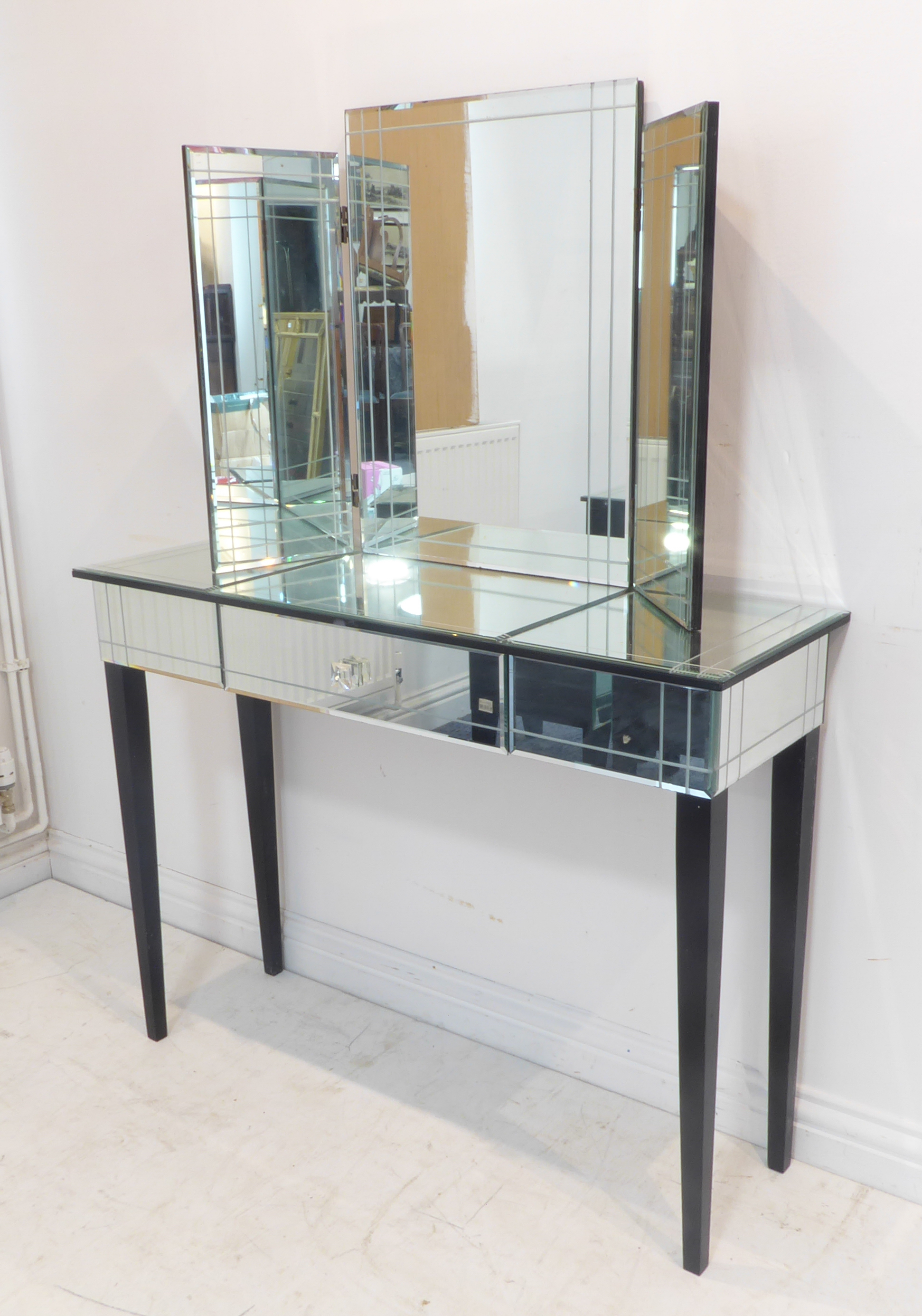 A modern dressing table and matching freestanding three-section mirror. The dressing-table with