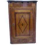 A late 18th century George III period oak and banded hanging corner cupboard; the panelled door