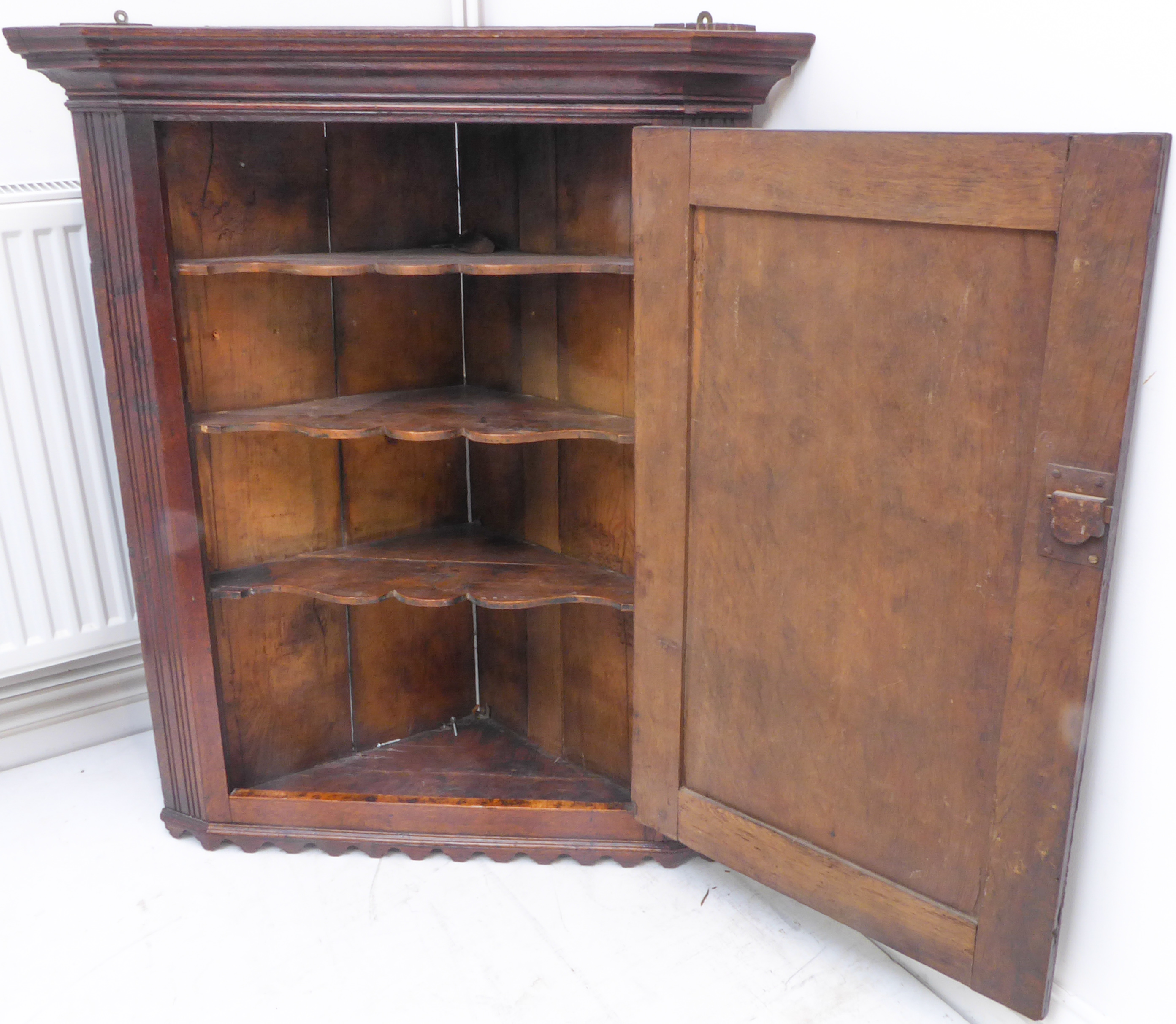 A late 18th century oak hanging corner cupboard; the single fielded panel door with brass H-form - Image 2 of 2