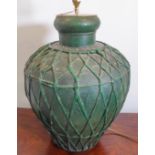 A large baluster-shaped green-painted tin lamp with woven latticework-effect decoration in relief