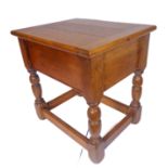 An oak joint-style stool with cleated hinged top and turned legs united by moulded stretchers