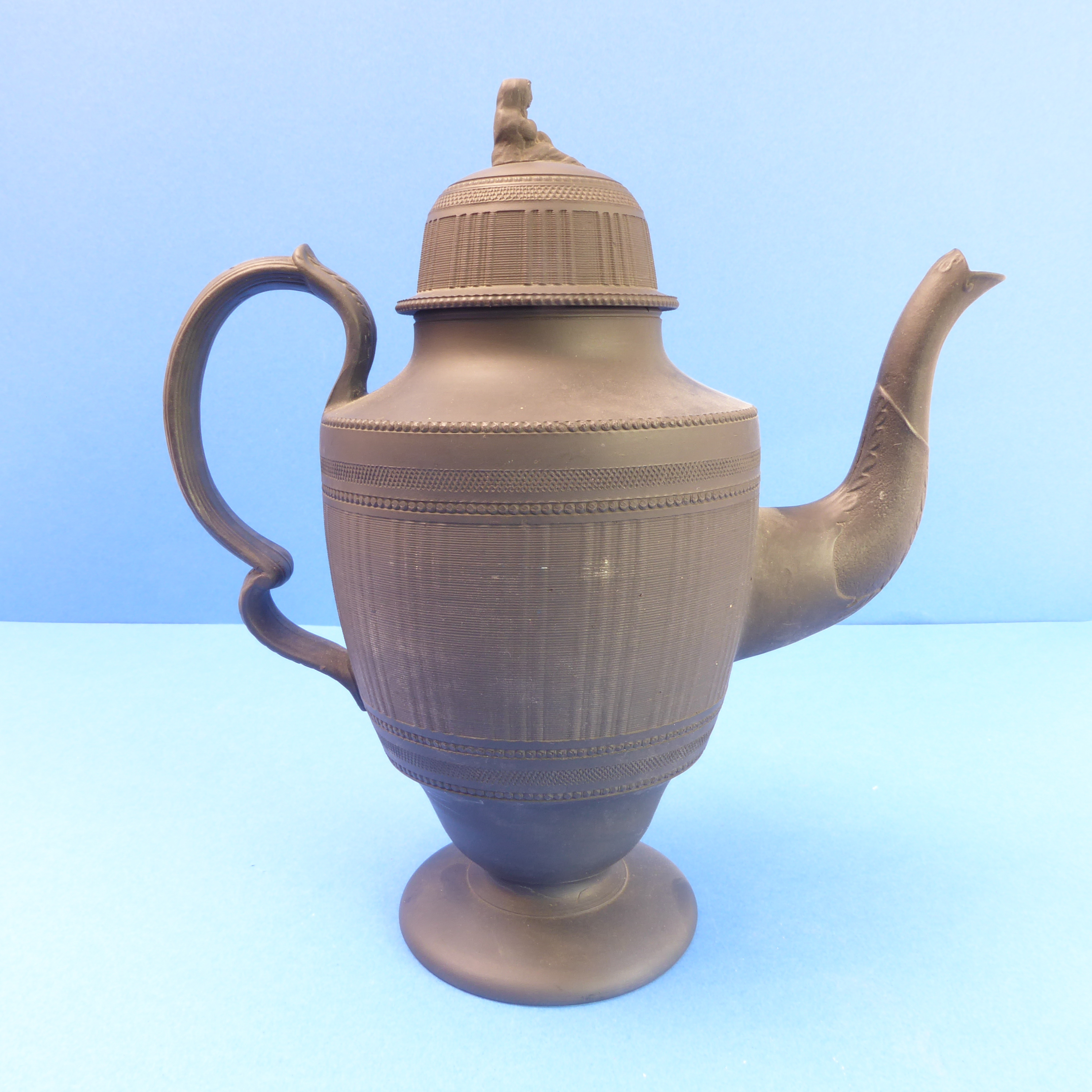 A 19th century black basalt teapot and cover with figurine finial (31cm high)Cover is fine; no