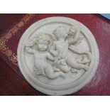 A classical-style marbleised circular wall relief depicting two winged cherubic-style figures (