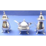 An early 20th century three-piece hallmarked silver cruet set to include a pair of peppers and a