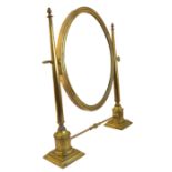 A brass dressing table swing-mirror with oval bevelled glass and frame