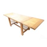 An oak extending draw leaf refectory-style table; the cleated top exhibiting exposed pegs in Arts