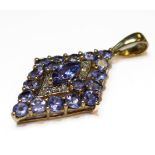 A 9-carat yellow-gold lozenge-shaped pendant centrally set with an elyptical tanzanite within a