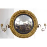 A large early 19th century circular gilt framed convex looking glass; the frame as a laurel leaf