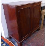 A George III period mahogany side cabinet; the two figured panelled doors opening to reveal