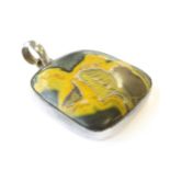 A hallmarked silver pendant set with an irregularly shaped polished hardstone exhibiting yellow,