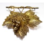 A silver-gilt filigree-style brooch modelled as leaves and berries within metal-mounted dome-