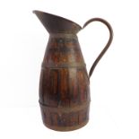 A late 19th/early 20th century brass coopered oak jug of large proportions; angular copper spout and