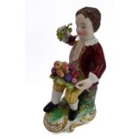 A hand-decorated Derby-style porcelain figure of a young boy - seated and holding in his right