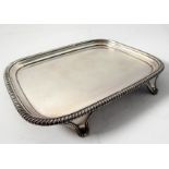 A hallmarked silver salver of rectangular shape; raised gadrooned border and on four shaped feet,