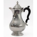 A hallmarked silver hot water jug of baluster form and high arched scrolling ebonised handle,