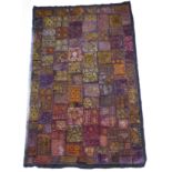 An intricate hand-stitched Indian wall hanging of multi-coloured design, some of the varying