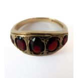 A 9-carat yellow gold garnet-set ring, the five graduated garnets gypsy-set with the engraved mount,